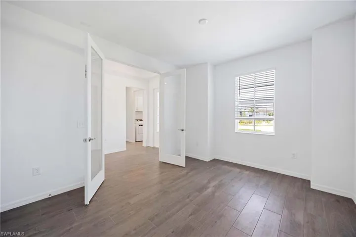 Empty room featuring french doors, dark wood finished floors, washer / clothes dryer, and baseboards