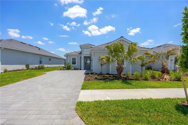 View of front of property featuring decorative driveway, a front lawn, stucco siding, and a tile roof