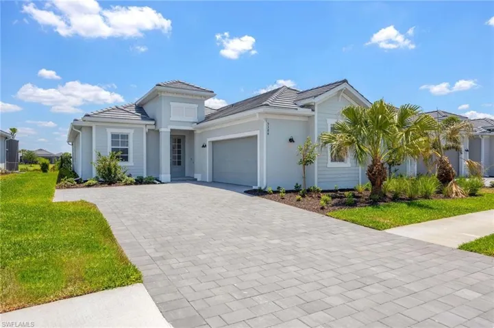View of front of home with decorative driveway, a garage, a front lawn, and a tile roof