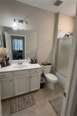 Full bath featuring vanity, shower / bath combination with glass door, and light tile patterned flooring