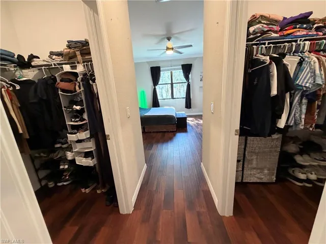 Him & Her Walk in closets featuring dark wood-type flooring and ceiling fan