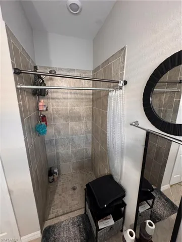 Full bathroom with a shower stall and baseboards