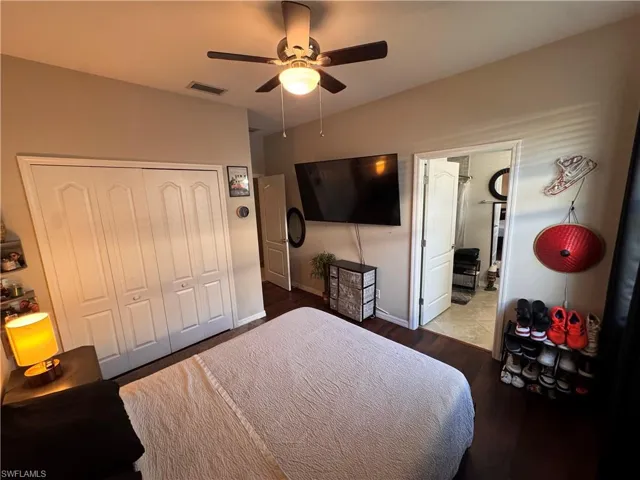 Bedroom with wood finished floors, a closet, a ceiling fan, and connected bathroom