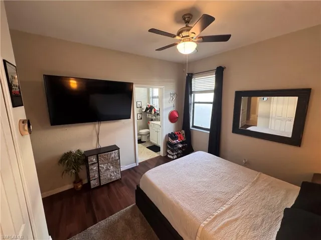 Bedroom with ensuite bathroom, dark wood finished floors, and a ceiling fan