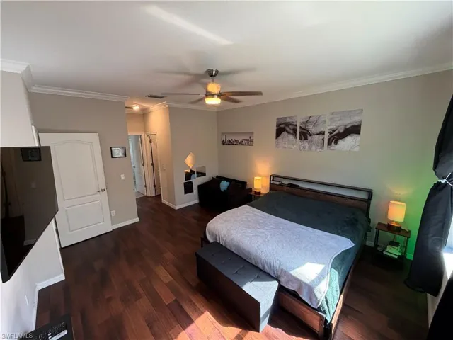 Master bedroom with ornamental molding, dark wood finished floors, a closet, and ceiling fan