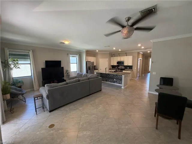Living area with ceiling fan, crown molding, light tile patterned floors, and recessed lighting