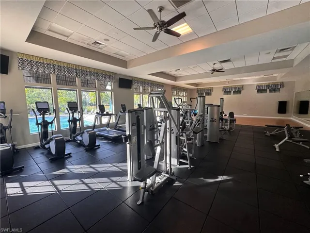 Exercise room with ceiling fan and a raised ceiling