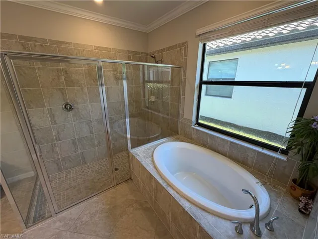 Full bath featuring a bath, a stall shower, and crown molding