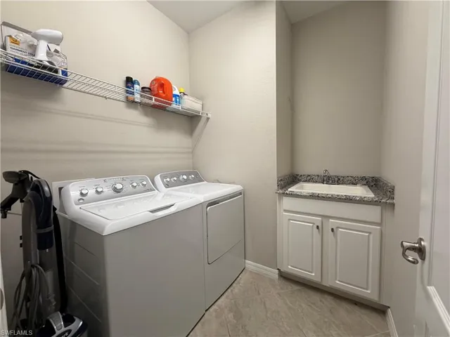 Laundry room featuring separate washer and dryer, cabinet space, and light tile patterned floors