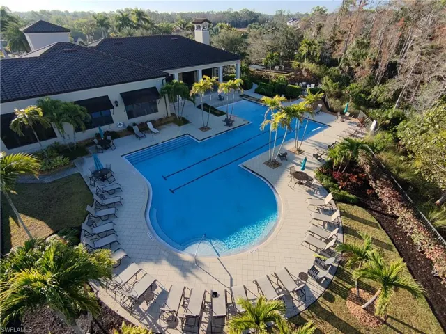 Community pool with a patio and view of wooded area