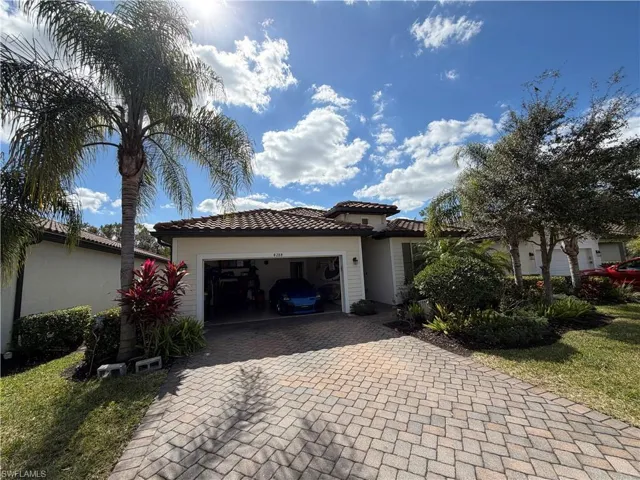 View of front facade with decorative driveway, a tile roof, and a garage