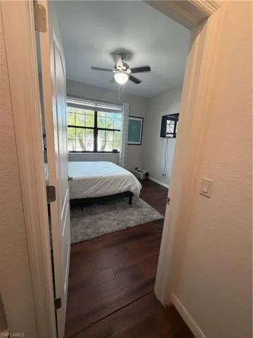 Bedroom featuring dark wood finished floors, ceiling fan, a textured wall, and a closet