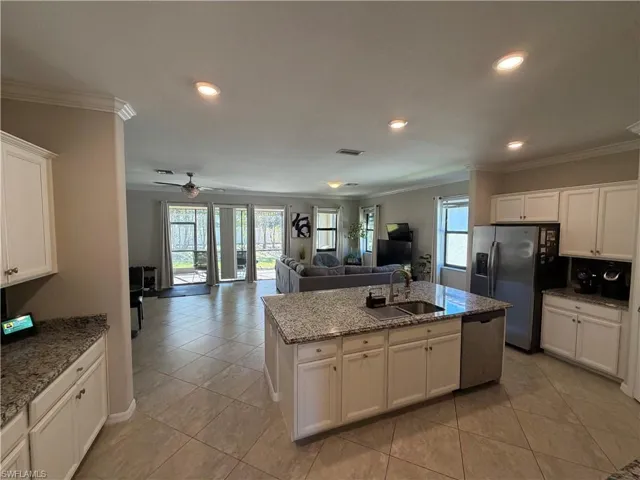 Kitchen featuring white cabinets, open floor plan, a kitchen island with sink, recessed lighting, and stainless steel appliances