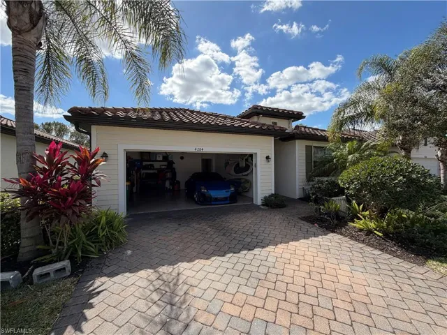 View of front of home featuring decorative driveway, a tile roof, and a garage