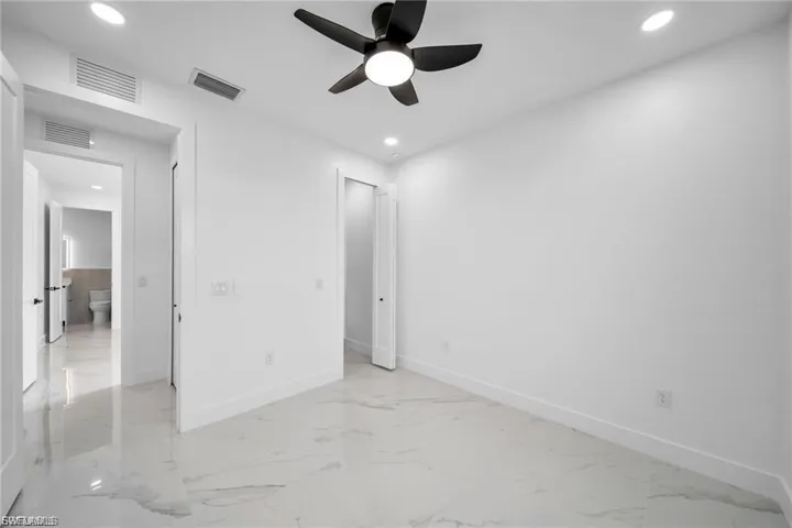 White walls, marble-finish tile flooring, recessed lighting, and a ceiling fan with light fixture