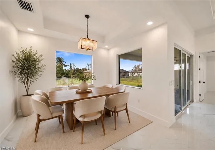 Recessed lighting, tray ceiling, sliding glass doors, large windows, and polished tile flooring