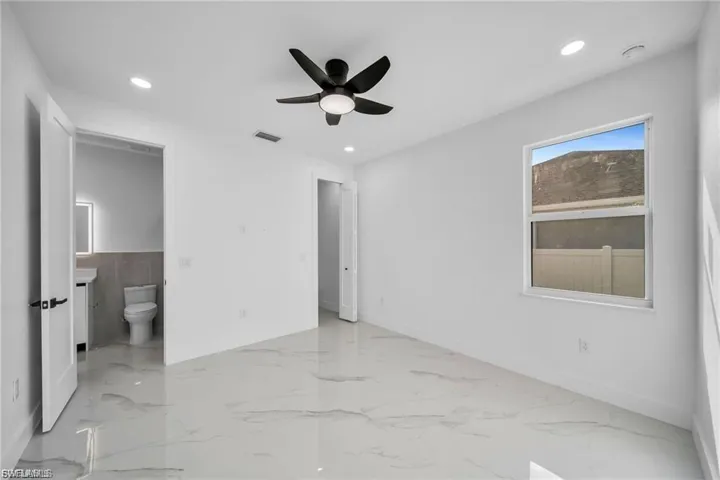 White walls with recessed lighting, a ceiling fan, and large format tile flooring