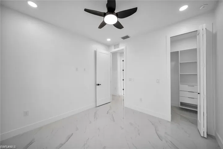 White walls with recessed lighting and a ceiling fan