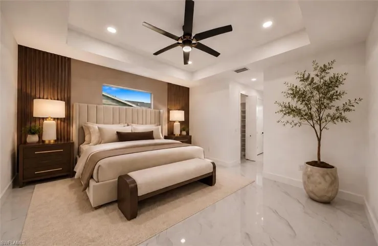 Tray ceiling with recessed lighting, wood-panel accent wall, horizontal window, ceiling fan with light, and polished tile flooring