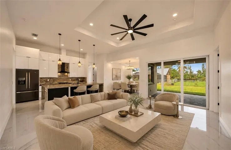 Open-concept living area with tray ceiling, recessed lighting, and a modern ceiling fan