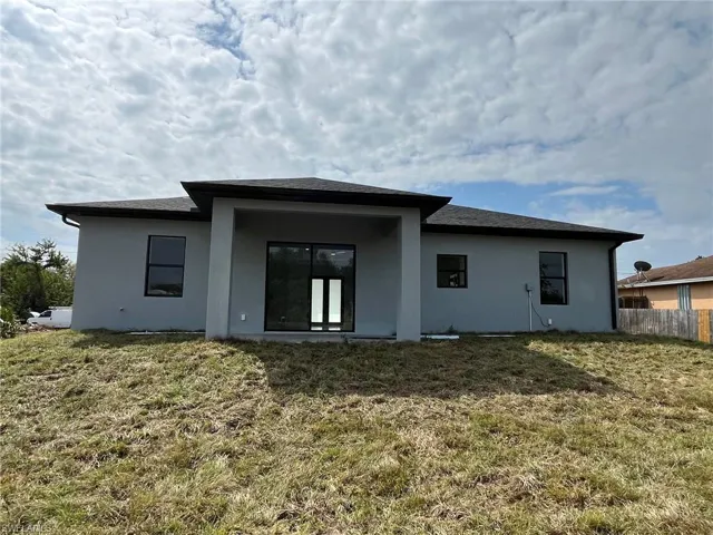 Back of house with a yard, fence, and stucco siding