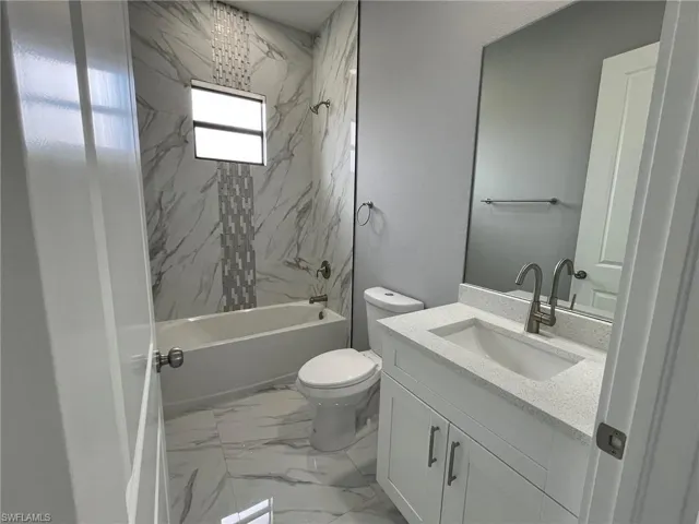 Full bathroom featuring marble finish floor, vanity, toilet, and shower / bathtub combination