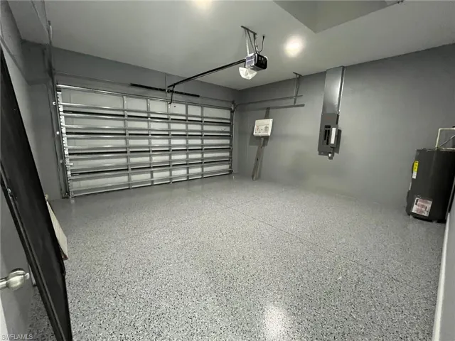 Garage with electric panel, a garage door opener, and electric water heater