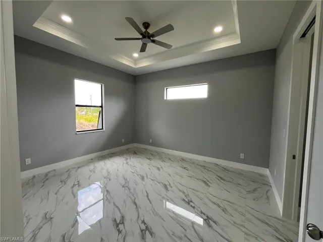 Empty room featuring a tray ceiling, a healthy amount of sunlight, and baseboards