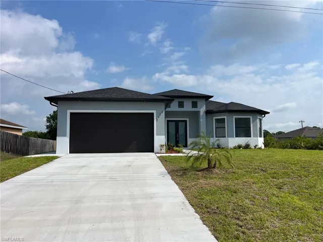 Prairie-style home featuring a front yard, a garage, concrete driveway, french doors, and stucco siding