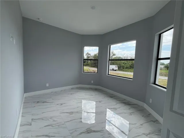 Unfurnished room featuring marble finish floor and baseboards