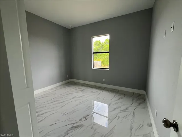 Spare room featuring marble finish floor and baseboards