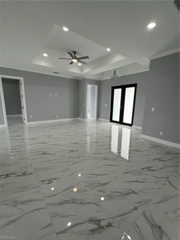 Unfurnished room with ornamental molding, french doors, a raised ceiling, and baseboards
