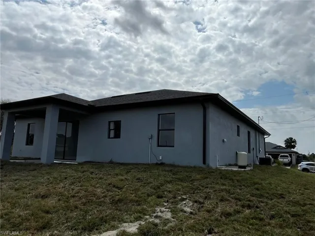 View of property exterior with a lawn and stucco siding