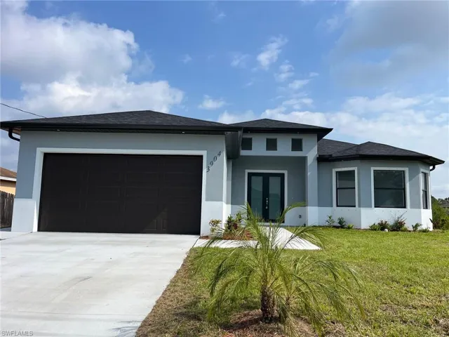 Prairie-style home featuring a garage, stucco siding, a front yard, french doors, and driveway