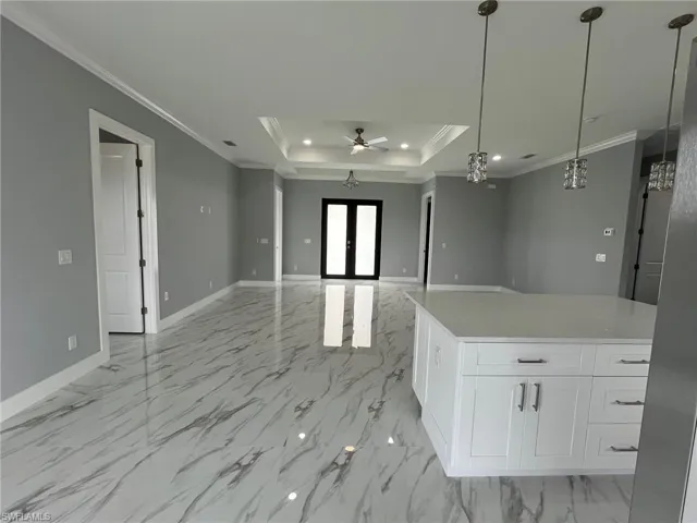 Kitchen with baseboards, white cabinets, ornamental molding, a tray ceiling, and french doors