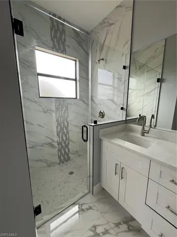 Bathroom with marble finish floor, vanity, and a marble finish shower
