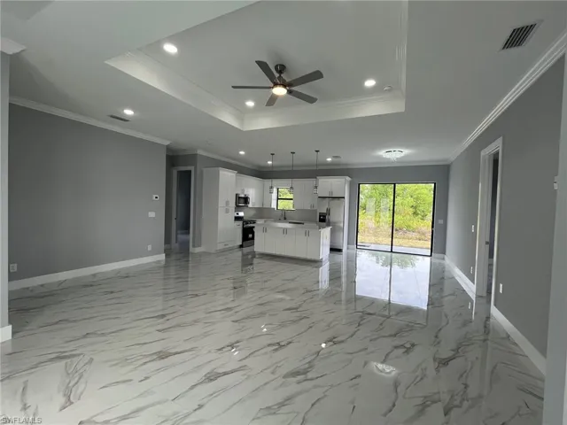 Unfurnished living room with baseboards, visible vents, a raised ceiling, ornamental molding, and recessed lighting