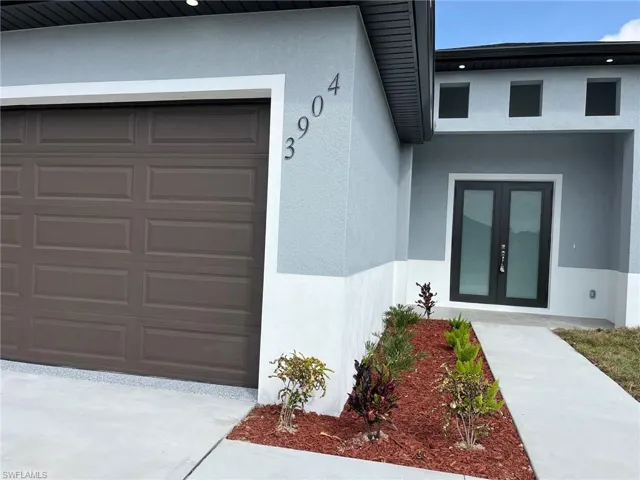 View of exterior entry with french doors, an attached garage, and stucco siding