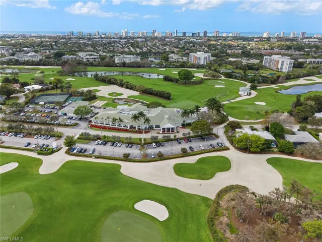 Aerial view of a golf club, a large body of water, and skyline