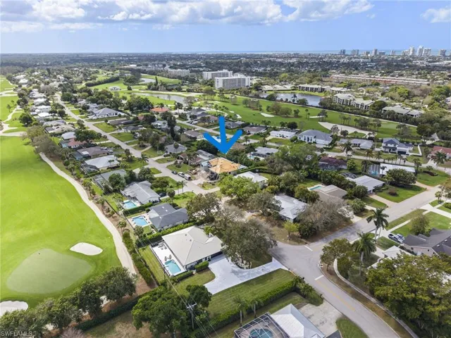 Aerial perspective of suburban area featuring a golf course and a nearby body of water