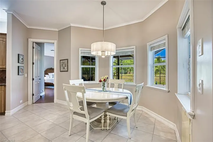 Dining area off kitchen with tiled floors crown molding and great pool view