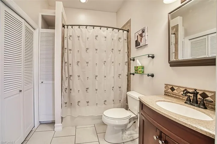 Full bath featuring shower / bath combo, a closet, toilet, vanity, and tile patterned floors ensuite off of 4th bedroom/office