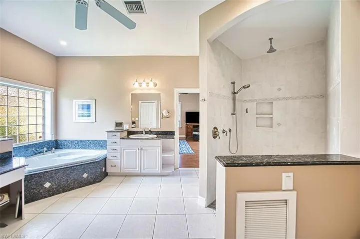 Bathroom with tile floors, a ceiling fan, a jetted tub and large shower