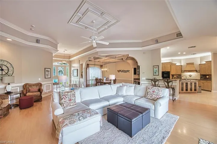Living room featuring arched walkways, ornamental molding, a ceiling fan, and light wood-type flooring