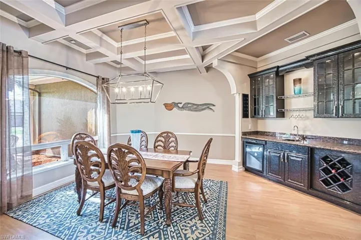 Dining area with arched walkways, luxury vinyl flooring, wet bar, coffered ceiling