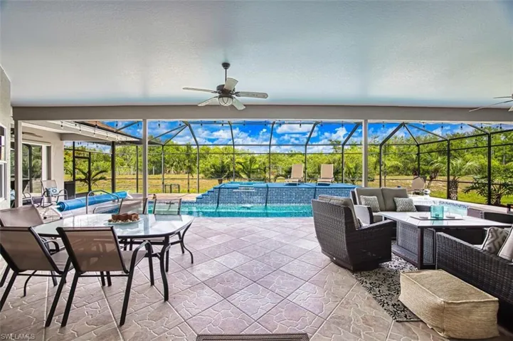 Pool with an outdoor living space, a patio area, a lanai, and a ceiling fans as well as an outdoor kitchen