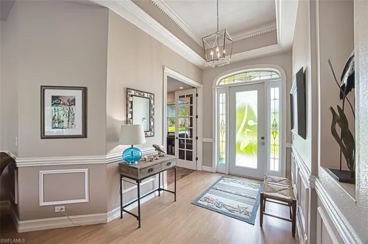 Foyer featuring ornamental molding, a raised ceiling, an inviting chandelier, and luxury vinyl floors