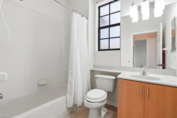 Full bathroom featuring vanity, shower / bath combination with curtain, and light tile patterned flooring