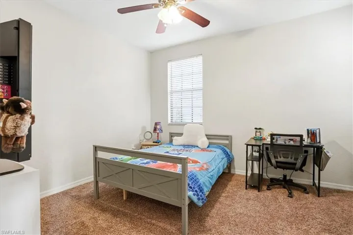 Carpeted bedroom with a ceiling fan and a desk