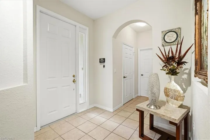 Foyer entrance featuring arched walkways, light tile patterned floors, and a textured wall